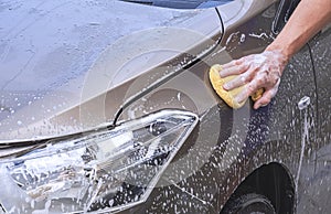 Man's hand using sponge and foam to washing car