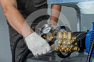 A man`s hand in a white glove turns on a set with a pressure gauge for testing high pressure hydraulic hoses