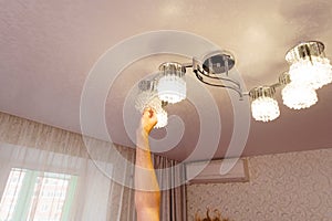 a man's hand will replace the bulbs in the chandelier lampshades.