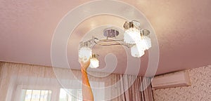 a man& x27;s hand will replace the bulbs in the chandelier lampshades.