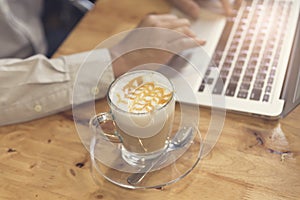 man's hand working with laptop computer with cup of hot latte co