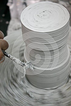 Man`s hand working on potter`s wheel with a chisel.