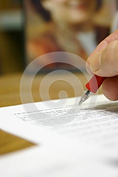 Man's hand writing at desk grading a paper