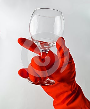 A man& x27;s hand in a yellow latex glove holds a clean glass wine gl