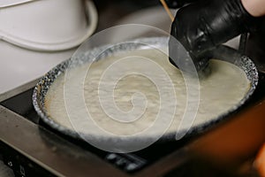 Man`s hands in black gloves cooking pancakes