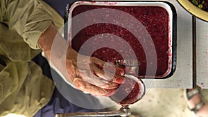 Man`s hands chops summer berries for jam in grinder closeup.