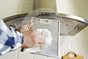 Man`s hands cleaning aluminum mesh filter for cooker hood. Housework and chores. Kitchen cooker hood on the background