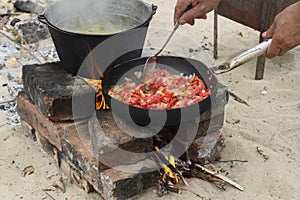 man`s hands coock in black iron pan roasting vegetables.