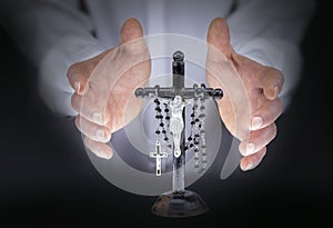 Man's hands with crucifix and a black rosary