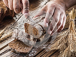 Man's hands cutting bread.