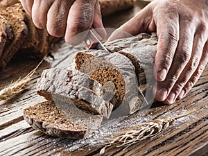 Man's hands cutting bread.