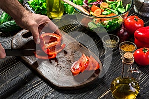 Man`s hands cutting red paprika with knife. Cook cut red paprika. Man loves cooking fresh salad for dinner. Paprika cut