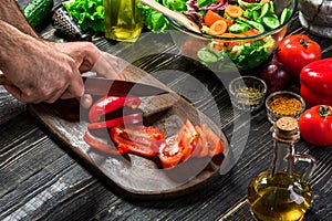 Man`s hands cutting red paprika with knife. Cook cut red paprika. Man loves cooking fresh salad for dinner. Paprika cut