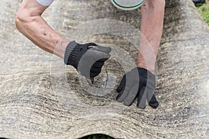 Man`s hands cutting roofing material. Ruberoid. Condtruction.