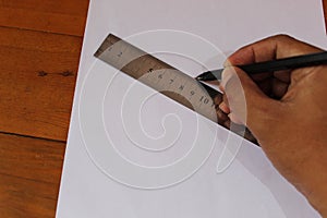 man`s hands drawing on paper. Top view of human hands, paper, pencils, ruler on a wooden table