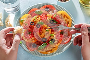 Man`s hands eating homemade tomato carpaccio with bread and fork.