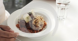 Man`s hands eating a meal of rice and mushrooms, Swedish meatballs on a bed of carrots with parmesan slices on top