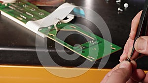 Man`s hands fix microswitch of electrical card using tweezers.