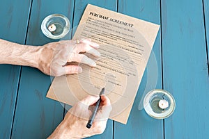 Man's hands with fountain pen signing contract next to lit candles