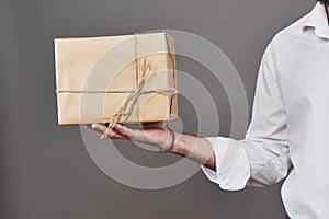 Man`s hands gives parcel wrapped in brown paper and tied with rough twine