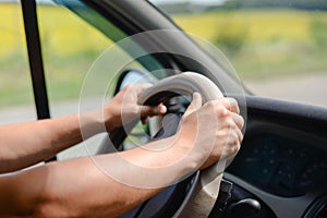 Man's hands gripping wheel of car