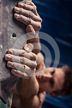 Man`s hands on handhold on artificial climbing wall