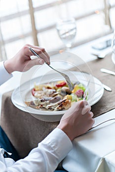 Man`s hands with healthy vegetarian meal on table in restaurant.