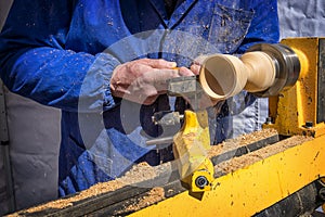 Man`s hands hold chisel near lathe