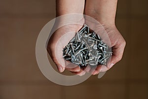 Man`s hands hold several screws.