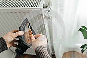 The man& x27;s hands hold a wallet with money next to the radiators. The concept of increasing prices for gas and energy