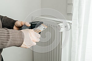 The man& x27;s hands hold a wallet with money next to the radiators. The concept of increasing prices for gas and energy