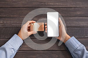 Man`s hands holding credit card and cellphonewith blank screen