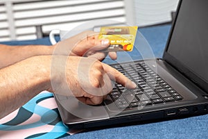 Man`s hands are holding a credit card and using laptop. Online shopping