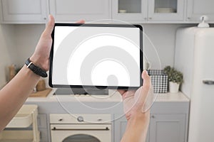 Man`s hands holding digital tablet empty screen in kitchen room.