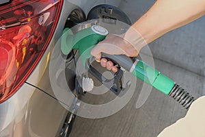 Man`s hands holding the gas pump and filling the car with fuel close-up. Energy industry. Gas station business/market.
