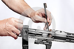 Man`s hands holding rifle parts details and cleaning the gun by metal brush