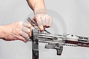 Man`s hands holding rifle parts details and cleaning the gun by metal brush