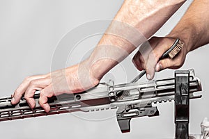 Man`s hands holding rifle parts details and cleaning the gun by metal brush