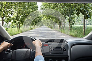 Man`s hands holding steering wheel and road background