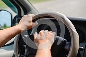 Man's hands holding a wheel of a car and beeping a