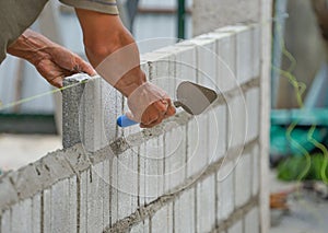 Man`s hands  of industrial bricklayer with  aluminium brick trowel installing brick blocks on construction site