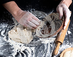Man`s hands knead white wheat flour dough