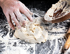 Man`s hands knead white wheat flour dough