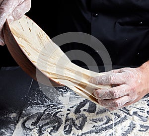 Man`s hands knead white wheat flour dough