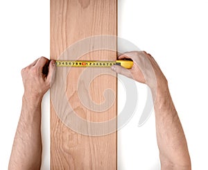 Man's hands measuring wooden plank with a tape line isolated on white background
