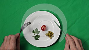 A man's hands move closer to the plate of meager food. Portion control. The concept of weight loss and healthy