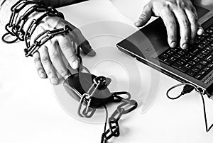 Man`s hands in old rusty chains. In the trap of office work. Routine job. Manager near the laptop. Black and white