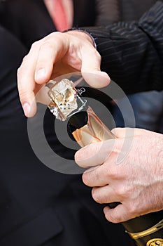 The man's hands opening a bottle of champagne