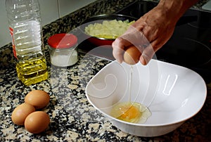 Man`s hands opening some eggs for cooking spanish omelette photo
