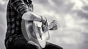 Man`s hands playing acoustic guitar, close up. Acoustic guitars playing. Music concept. Black and white
